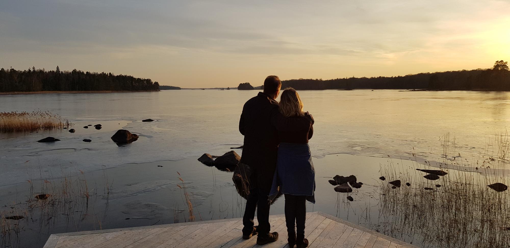 Ett par som tittar på solnedgång vid frusen sjö