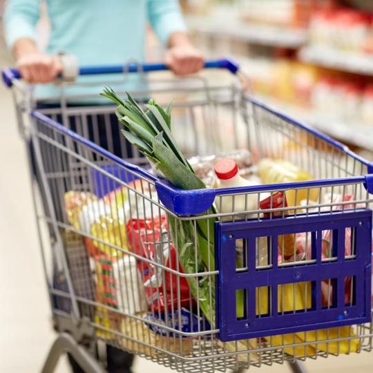 Woman with food in shopping cart at supermarket.